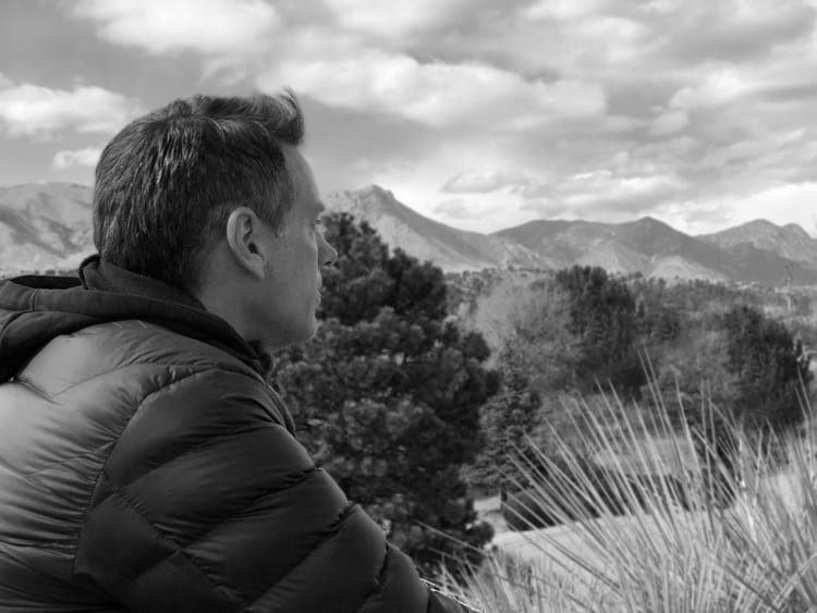 A black and white photo of me in a jacket overlooking the mountains of Colorado.