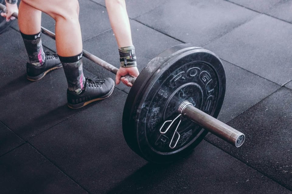 A man is at the gym standing and ready to lift a barbell. 
